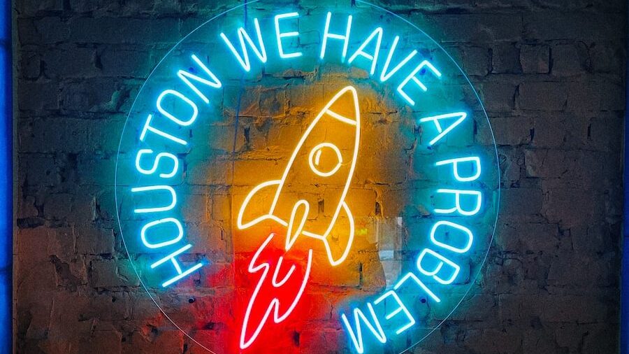 a neon sign that says houston we have a rocket on it